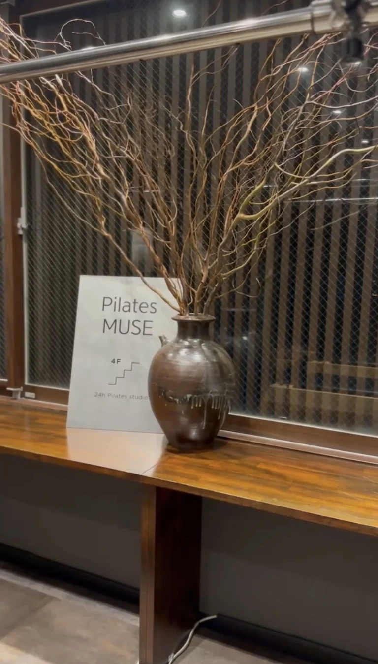 スタジオ内の生け枝とPilates MUSEの案内板